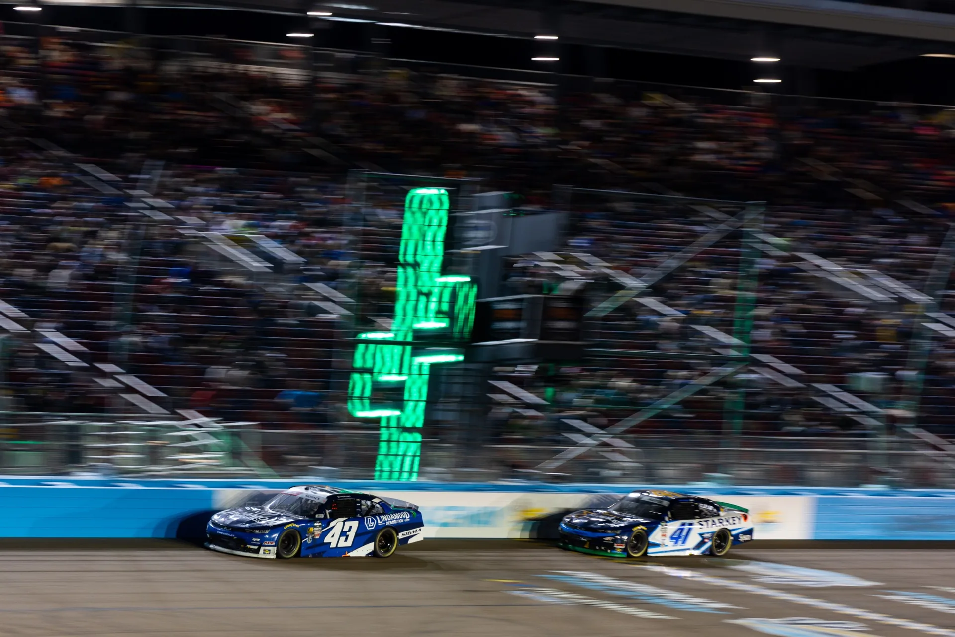 The No. 43 Lindamood Chevrolet and No. 41 race under the lights at Phoenix Raceway.