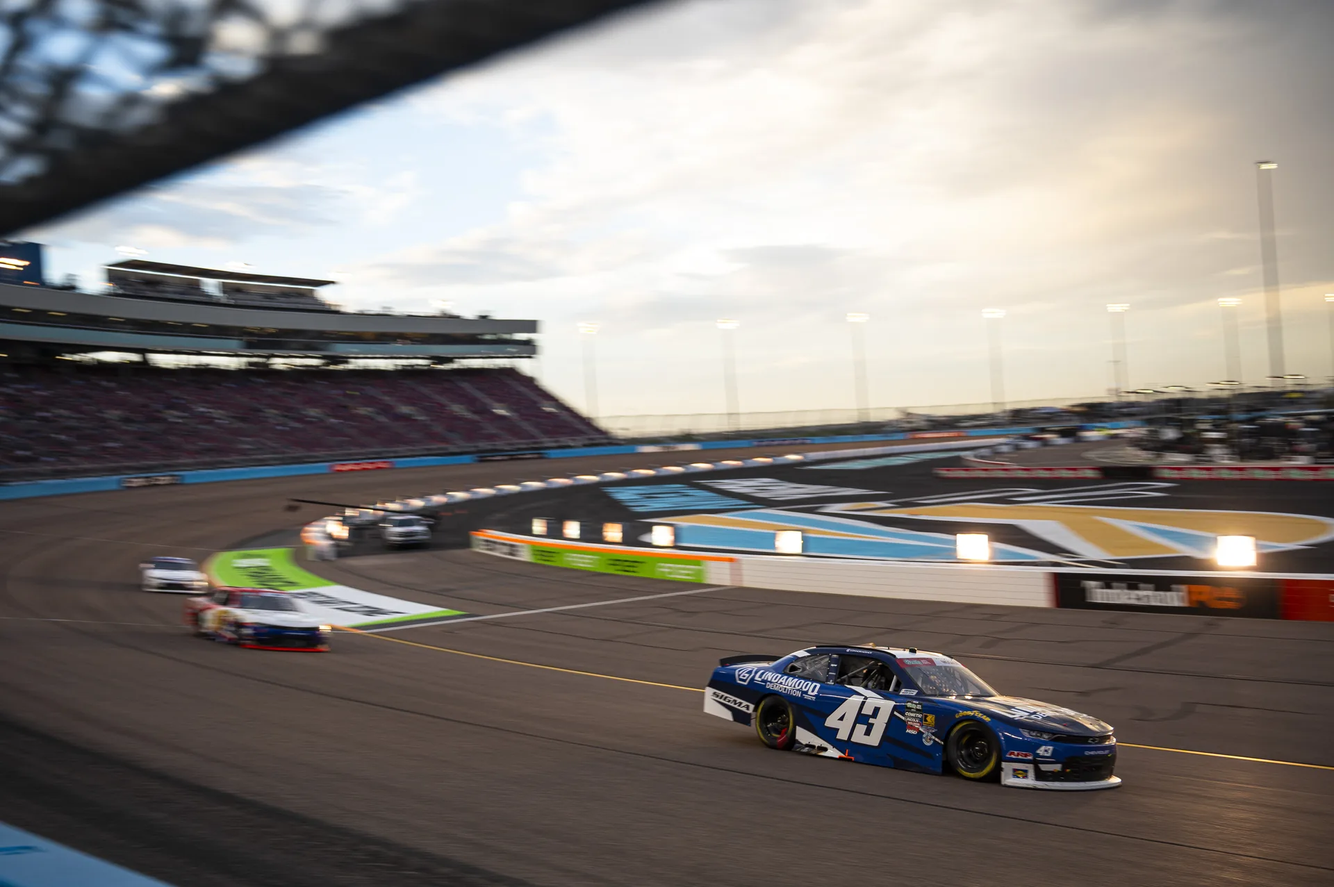 The No. 43 Lindamood Chevrolet passes the grandstands at Phoenix Raceway near sunset.
